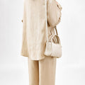 Ivory mini song bag made of textured full-grain leather, worn by a woman in a beige linen outfit.