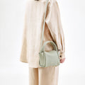 Mini Song Bag in Jade green full-grain leather with top handle and adjustable strap.