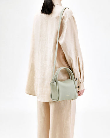 Mini Song Bag in Jade green full-grain leather with top handle and adjustable strap.