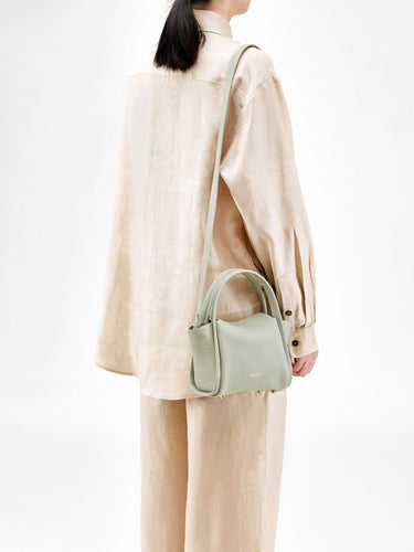 Mini Song Bag in Jade green full-grain leather with top handle and adjustable strap.