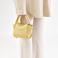 Lemon Mini Song Bag in pebbled leather with dual top handles and subtle embossed branding.