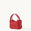 Red pebbled leather Mini Song Bag with curved top handle and gold foil logo. A chic, compact handbag for seasonal styling.