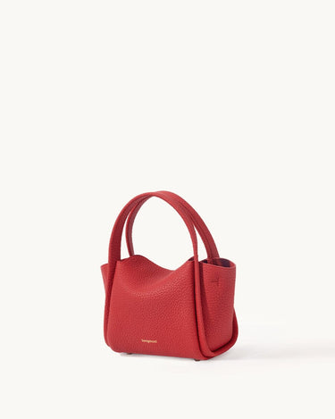 Red pebbled leather Mini Song Bag with curved top handle and gold foil logo. A chic, compact handbag for seasonal styling.