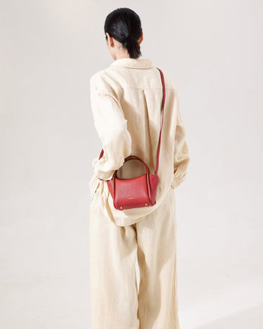 Mini Song Bag in lucky red pebbled leather, shown on a person from the back.