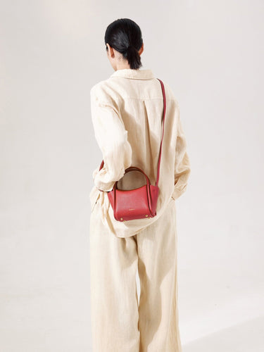 Mini Song Bag in lucky red pebbled leather, shown on a person from the back.