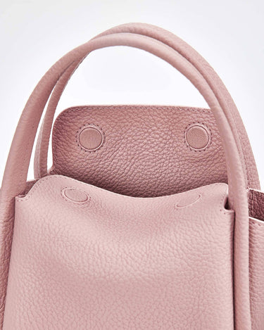 Pink full-grain leather Mini Song Bag with top handles and textured exterior.