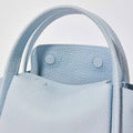 Sky blue mini leather bucket bag with textured finish and snap closure details.