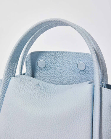 Sky blue mini leather bucket bag with textured finish and snap closure details.