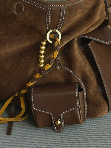Mini Yore AirPods Case in Sandal color, made of vegetable-tanned leather, attached to a suede bag.