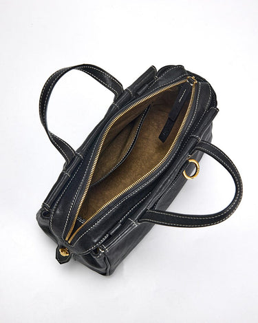 Black Mini Yore Duffle Bag: tan interior, gold zipper, white stitching. Compact leather travel bag.