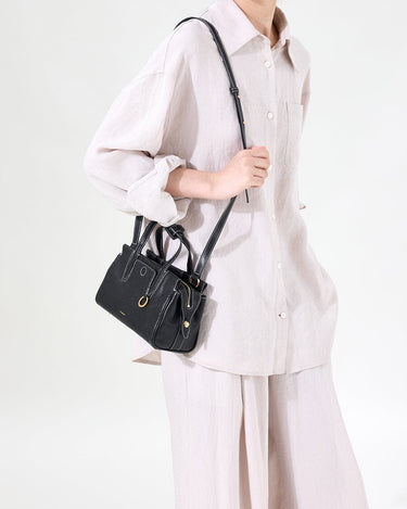 Black Mini Yore Duffle Bag made of vegetable-tanned leather with contrast stitching, worn crossbody by a woman in linen.