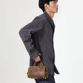 Mini Yore Duffle Bag in Sandal color, crafted from vegetable-tanned leather with gold hardware, held by a man.