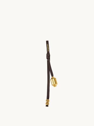 Sandal brown leather prayer wheel charm with gold hardware and "Songmont" logo.