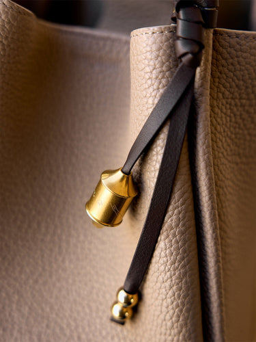 Sandal Prayer Wheel Charm with engraved golden cylinder and leather strap on pebbled leather handbag