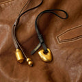 Gold prayer wheel charm with "Songmont" logo on a brown leather background.