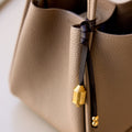 Sandal leather Prayer Wheel Charm with gold engraved pendant and double bead detail.