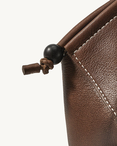 Prism Airpods Case, Sandal color: textured leather, white stitching, dark wood bead detail.