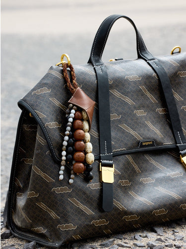 Sandal Prism Seed Charm with woven bodhi seeds and leather detailing attached to a patterned Songmont bag.