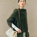 Amber shearling gather clutch set with leather strap, worn by a model in a green sweater.