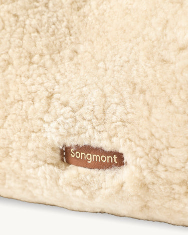 Songmont Shearling Gather Clutch Set in Amber, showcasing its soft shearling texture and leather logo tag.