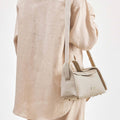 Ivory pebbled leather Small Drippy Roof Bag on person in beige linen.
