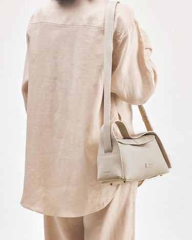 Ivory pebbled leather Small Drippy Roof Bag on person in beige linen.