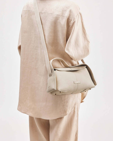Ivory textured leather Small Drippy Roof Bag worn crossbody, with gold hardware.