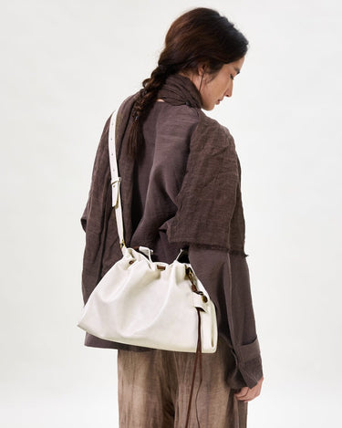 Small Gather Bag Set in Cloud, a cream leather tote with drawstring closure and white strap.