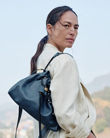 Navy Small Gather Bag Set carried by a woman, showcasing its textured leather and unique charm details.