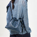Navy Small Gather Bag Set in smooth leather with drawstring closure, worn by a woman in a blue knit sweater.