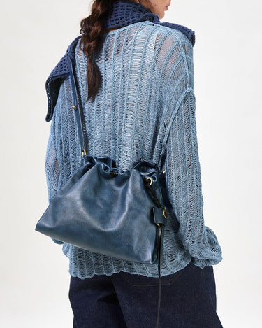 Navy Small Gather Bag Set in smooth leather with drawstring closure, worn by a woman in a blue knit sweater.