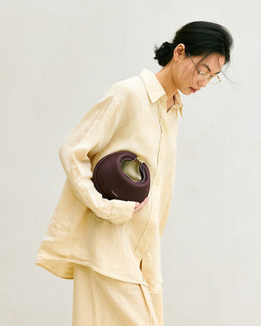 Woman holding the burgundy Small Luna Bag, featuring its rounded shape and textured leather.
