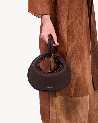Small Luna Bag in burgundy full-grain leather with a unique crescent shape and gold-tone hardware.