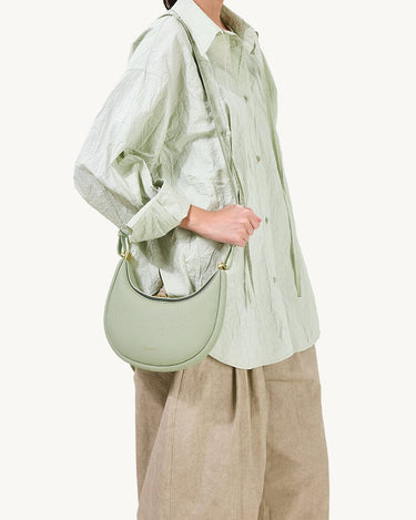 Small Luna Bag in Jade green pebbled leather with a curved silhouette and gold hardware.