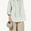 Jade pebble-grain Small Luna Bag with curved handle, paired with textured green shirt and beige pants.