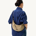 Medium Luna Hobo Bag in Dune Suede worn crossbody by a woman in a blue shirt and jeans.