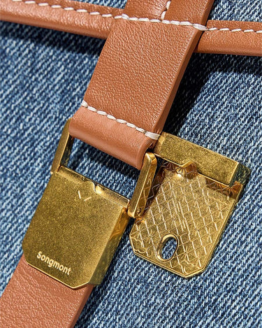 Small Shan Satchel Bag tan leather strap with gold clasp and Songmont logo on blue denim