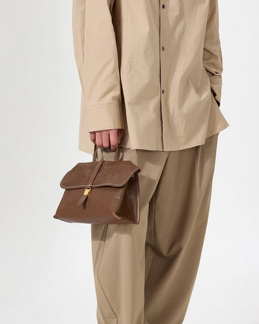 Small Shan Satchel Bag in Sandal brown vegetable-tanned leather with gold buckle detail.