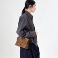 Small Shan Satchel Bag in Sandal color, made of vegetable-tanned leather with a golden clasp.