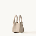 Small beige full-grain leather song bag with magnetic closure and gold hardware.