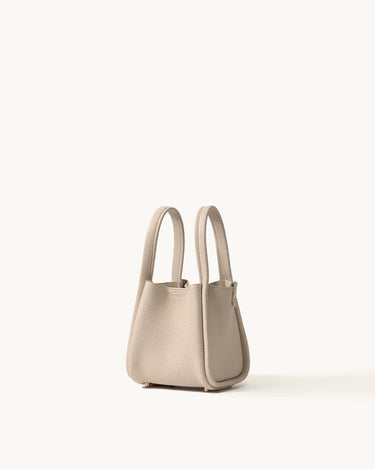Small beige full-grain leather song bag with magnetic closure and gold hardware.