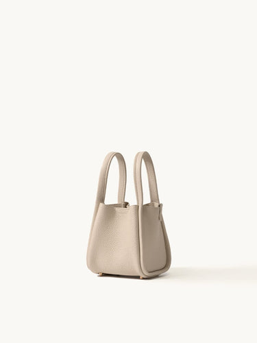 Small beige full-grain leather song bag with magnetic closure and gold hardware.