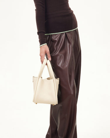 Small off-white full-grain leather song bag with magnetic closure and gold feet.