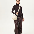 Small Song Bag in cream full-grain leather with magnetic closure, worn by a model.