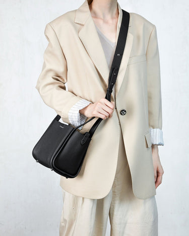 Black full-grain leather Small Song Bag with pebble texture and magnetic closure worn crossbody by a model.