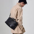 Small Yore Duffle Bag in Onyx, a textured black leather bag with white stitching worn over the shoulder.