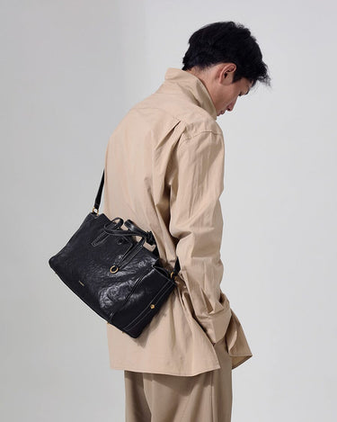 Small Yore Duffle Bag in Onyx, a textured black leather bag with white stitching worn over the shoulder.