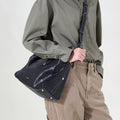 Small Yore Duffle Bag in Onyx, made from vegetable-tanned leather with gold hardware and white stitching, worn by a model.