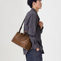 Small Yore Duffle Bag in Sandal brown leather, worn by a man over the shoulder.