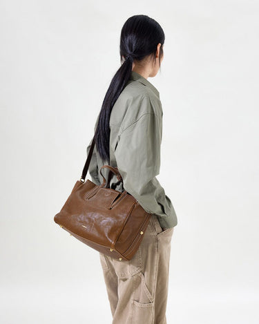 Small Yore Duffle Bag in Sandal brown leather, adjustable strap, brass hardware, detailed stitching. Versatile travel bag.